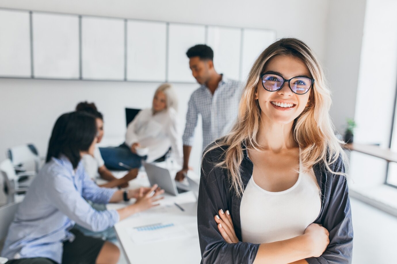 Smiling professional  woman standing in front of colleagues in a meeting